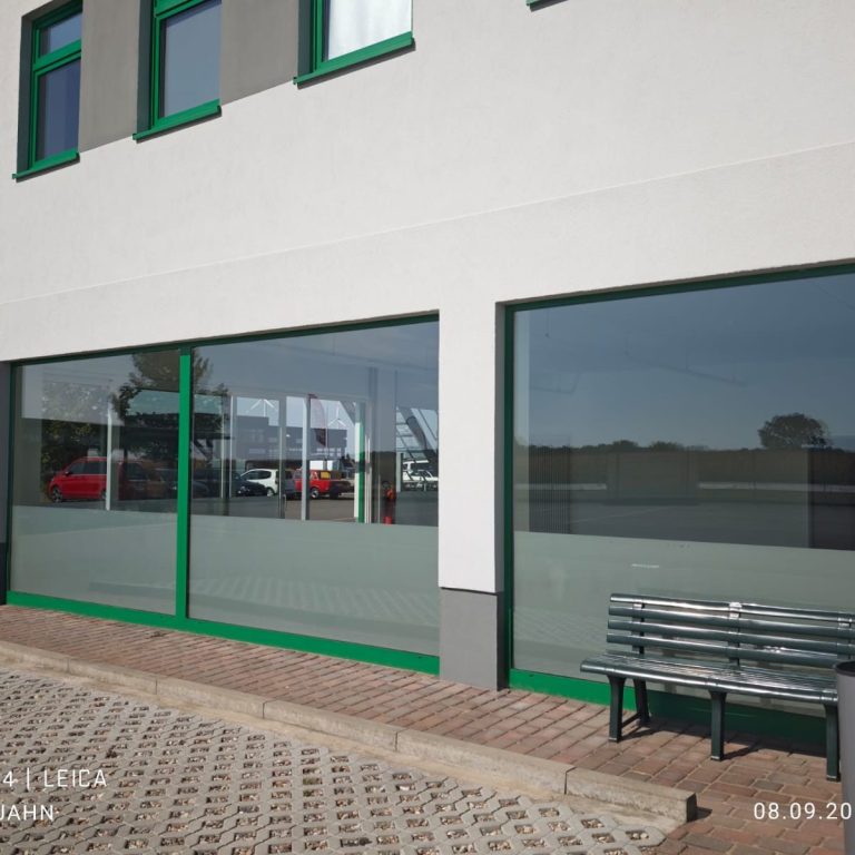 Moderne Fassade eines Gebäudes mit großen Fenstern und einem wartenden Bank.